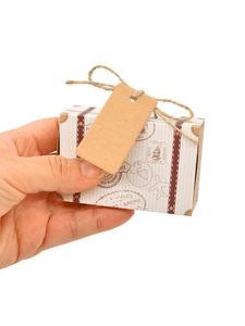 Detailed view of mini suitcase favor box with vintage travel stamps and kraft tag