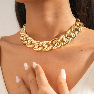 Close-up of a bold gold Cuban link necklace with polished finish on female model neck