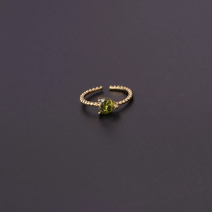 Macro detail of adjustable gold ring with green heart-shaped zircon and beaded texture