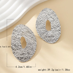 Macro detail of large silver earrings with lava texture showing size and weight specs