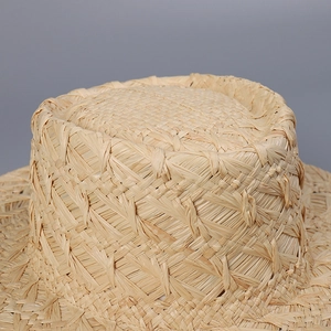 Detailed macro view of handcrafted raffia boater hat showing coarse cross-weave texture