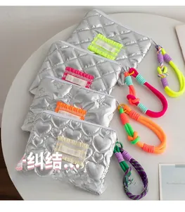 Close-up of silver quilted PU cosmetic bags with colorful ruffled edges and wrist straps