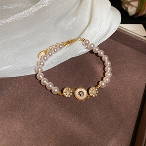Vue détaillée du bracelet en perles dorées 18k avec pendentif œil et cristaux