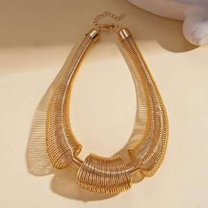 Detail of chunky gold spring coil necklace with high-gloss metallic finish and lobster clasp