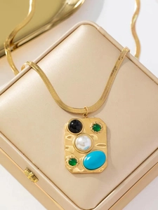 Détail d'un collier doré avec pendentif en pierres précieuses sur une boîte à bijoux beige