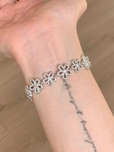 Detail of silver lace flower bracelet on wrist featuring dainty five-petal floral link charms