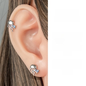 Detailed view of silver jellyfish stud earrings with blue teardrop zircon on the ear