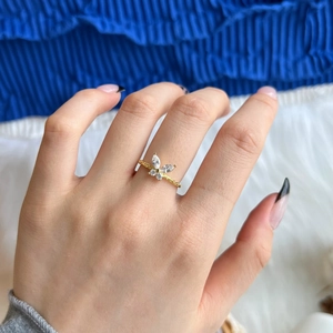 Close-up of gold butterfly ring with white zircon stones worn on finger