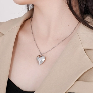 Gros plan sur un pendentif cœur argenté aux multiples facettes avec chaîne en titane