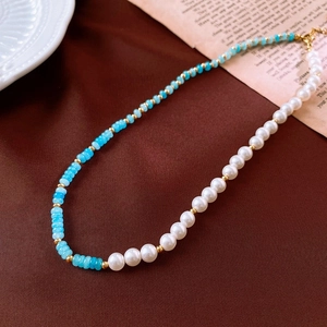 Detail of vintage necklace with blue faceted beads and white pearls on brown fabric