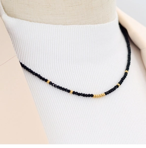 Close-up of faceted black beads and gold accents on a minimalist beaded necklace