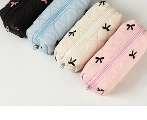 Quilted bow pencil cases in black, light blue, beige, and pink colors displayed together