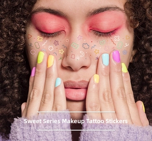 Macro shot of colorful star and cloud tattoo stickers on cheeks for sweet makeup looks