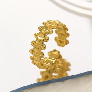 Detailed macro view of a gold pyramid stud ring with an adjustable open band design