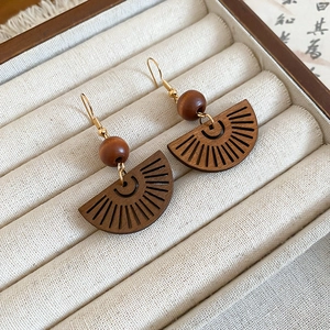 Gros plan détaillé de boucles d'oreilles en bois en forme d'éventail et métal