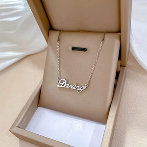 Detail of silver titanium steel necklace with Darling script pendant in a jewelry box