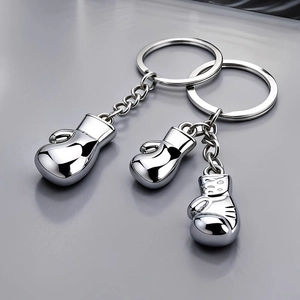Polished silver 3D metal boxing glove keychain pendants in two sets on dark background