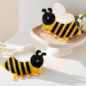 Detail showing two cute bee hair claws with acrylic texture and rhinestone accents