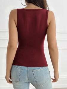 Πίσω όψη ενός μπορντό Y2K camisole top σε μοντέλο μπροστά από έναν ανάγλυφο τοίχο