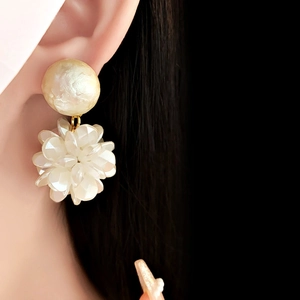 Close-up of elegant flower earrings with white petals and pearls on a model