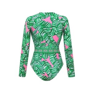 Detailed view of the tropical green leaf print and green waist belt on long sleeve swimsuit