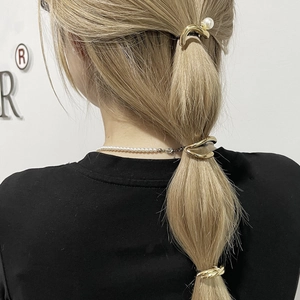 Three gold metal ponytail holders with pearl detail shown on hair for a punk look