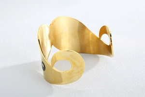 Detailed close-up of golden stainless steel cuff bracelet with hollow circle design