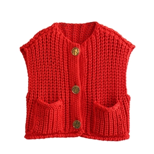 Detail of red chunky knit vest with large gold buttons and symmetrical front pockets