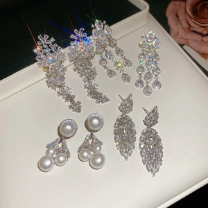 Detailed view of silver flower earrings with zircon tassels on a white display cushion