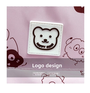 Dettaglio macro del logo 3D in silicone Happy Bear su uno zaino scolastico in tessuto rosa