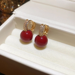 Detailed close-up of golden red zircon earrings in white jewelry gift box