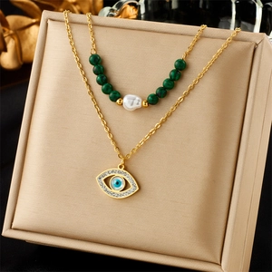 Detail of layered gold necklace with pearls, malachite beads, and evil eye pendant