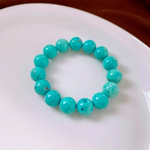 Macro view of blue turquoise round beads with natural mineral veins on a white tray