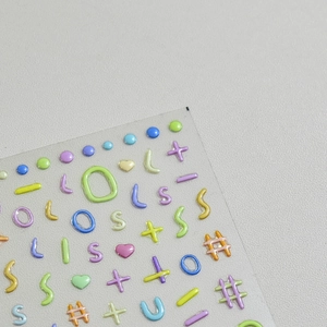 Macro view of 3D puffy alphabet and symbol nail stickers in pastel macaron colors