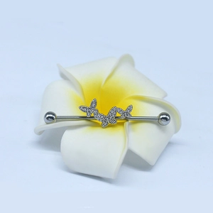 Macro shot of silver industrial barbell with three sparkling butterfly charms on a flower