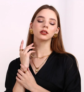 Close-up of elegant 18K gold plated geometric earrings and snake chain necklaces on model