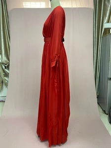 Detail of red long-sleeve maxi dress with waist belt and floor-length chiffon design