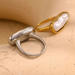 Detail of minimalist 18K gold and silver rings with baroque pearls on sandy texture