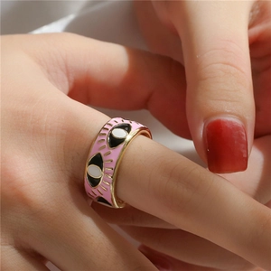 Close-up of pink enamel evil eye ring on finger showing detailed gold plating work