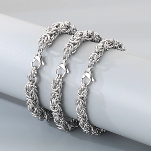 Polierte silberne Edelstahl-Byzantiner-Armbänder auf grauem zylindrischem Display
