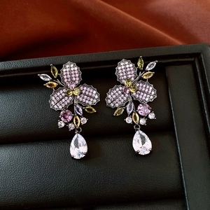 Dettaglio di orecchini a fiore vintage con zirconi colorati e finitura in oro nero
