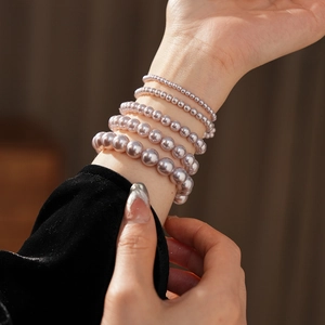 Detailed close-up showing layered champagne pink pearl bracelets with elegant lustrous finish