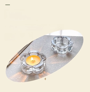 Detail of plum-shaped clear glass candle holder with tea light on textured surface