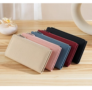 Five assorted colors of lychee grain leather long wallets stacked on a wooden table