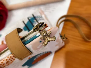 Detail of canvas pouch showing vintage bear metal zipper pull and faux leather handle