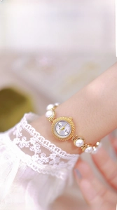 Close-up of elegant gold alloy women's watch with large white pearl bracelet strap