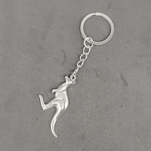 Detail of silver vintage metal kangaroo pendant keychain on a grey concrete background