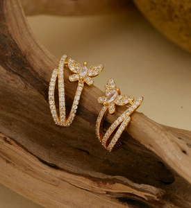 Macro shot of gold butterfly earrings with zircon stones hanging on a wooden branch