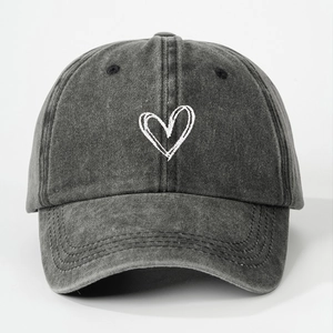 Close-up of dark grey washed denim baseball cap with white heart embroidery detail