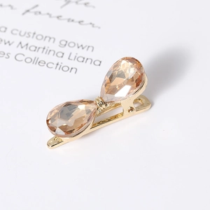 Detail view of crystal bow hair clip with champagne teardrop stones on gold metal base